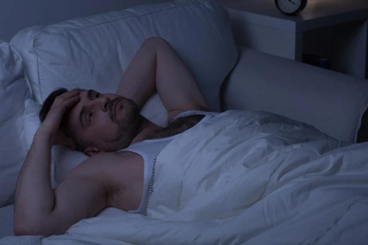 Uomo a letto cerca di prendere sonno 