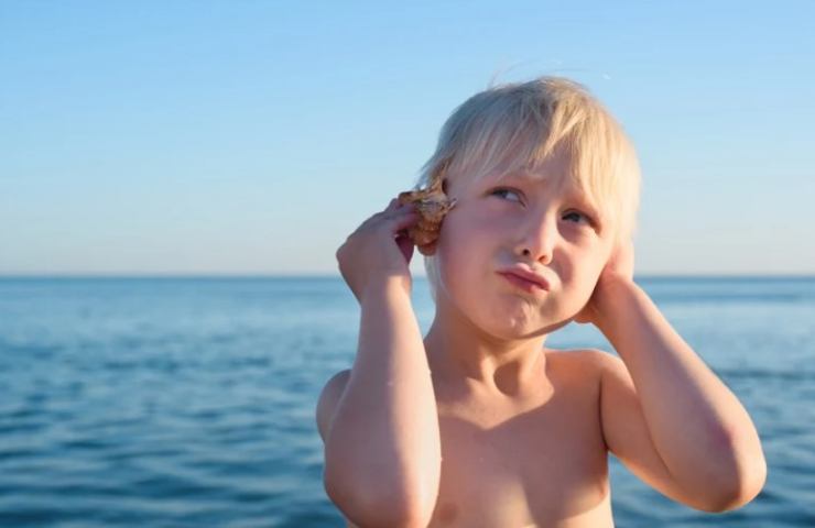 bambino ascolta il mare con una conchiglia