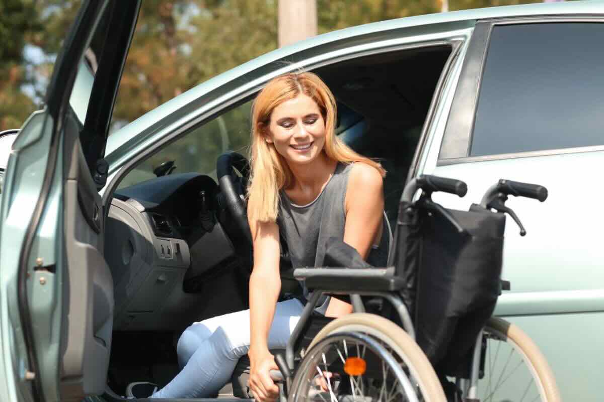 Donna disabile scende da auto carrozzina
