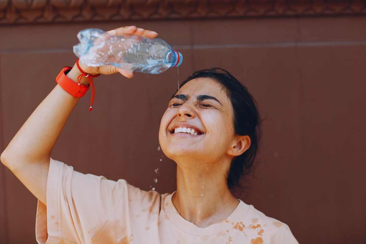 Ragazza che cerca sollievo dal caldo versandosi acqua sul viso