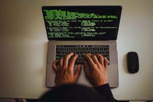 uomo incappucciato che inserisce codici in un PC