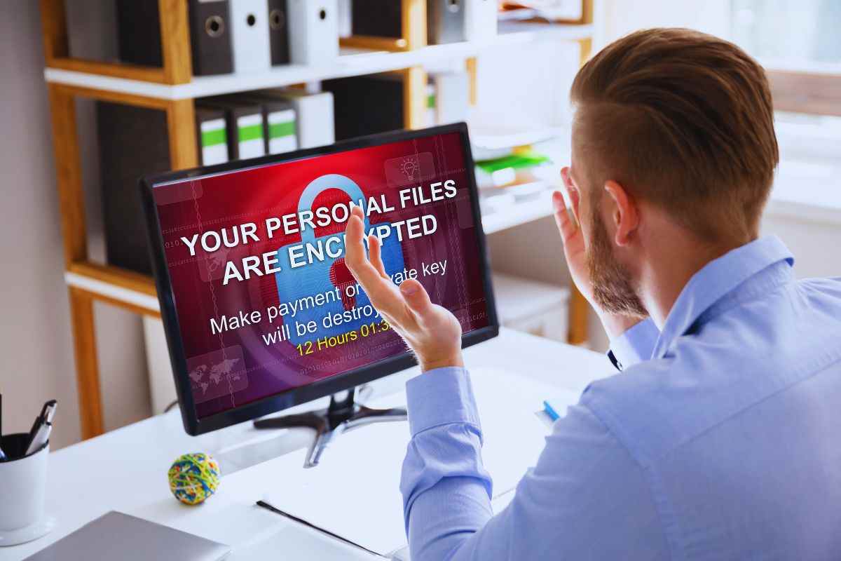 Uomo preoccupato da minaccia ransomware apparsa su schermo computer