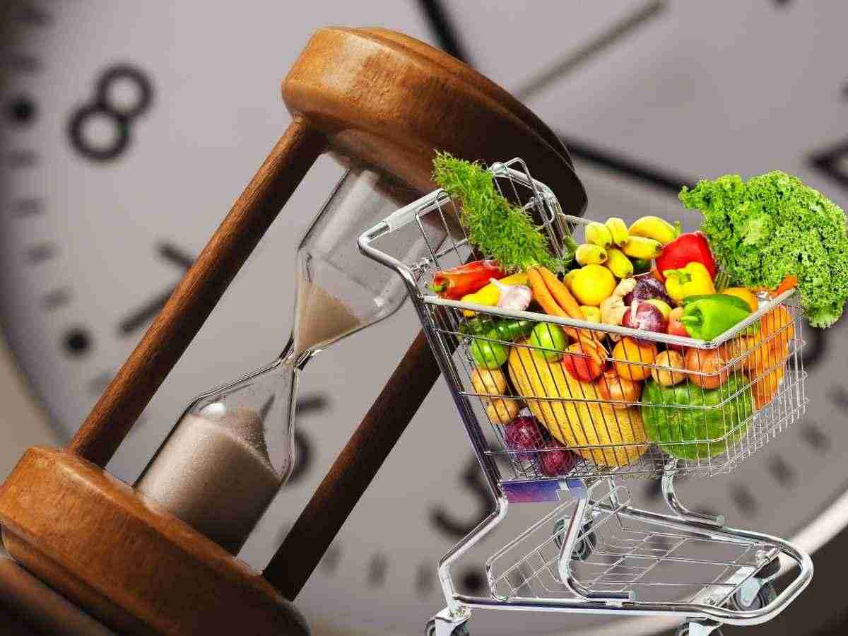 orologio e clessidra sullo sfondo, carrello spesa in primo piano