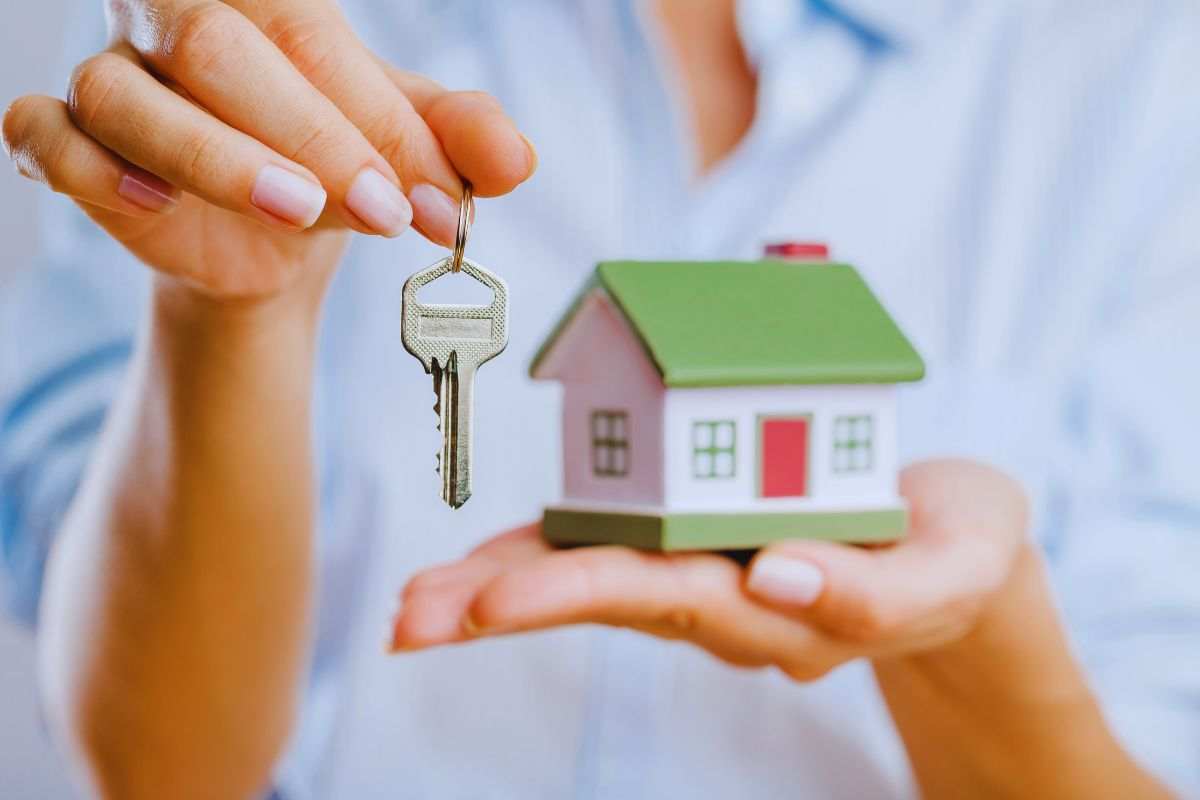 ragazza con in mano un modellino di casa e un mazzo di chiavi
