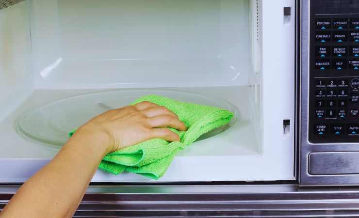 mano pulisce col panno l'interno del microonde